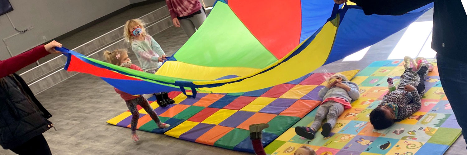 niños jugando con un paracaídas